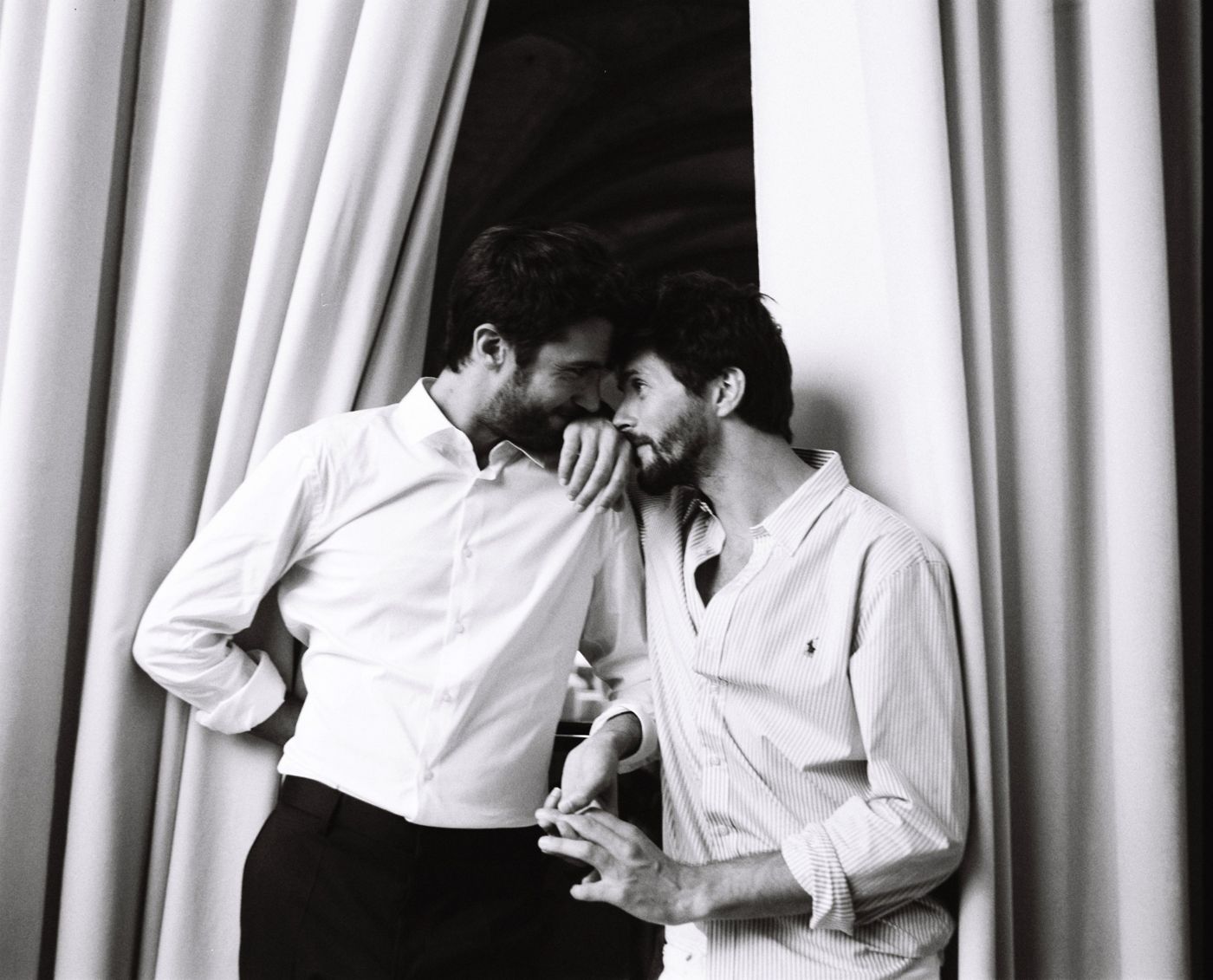 Two grooms by a curtain, black and white